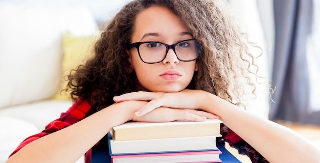 Adolescente reposant sur des livres dans la chambre