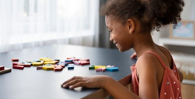 Smiley girl making puzzle vue de côté