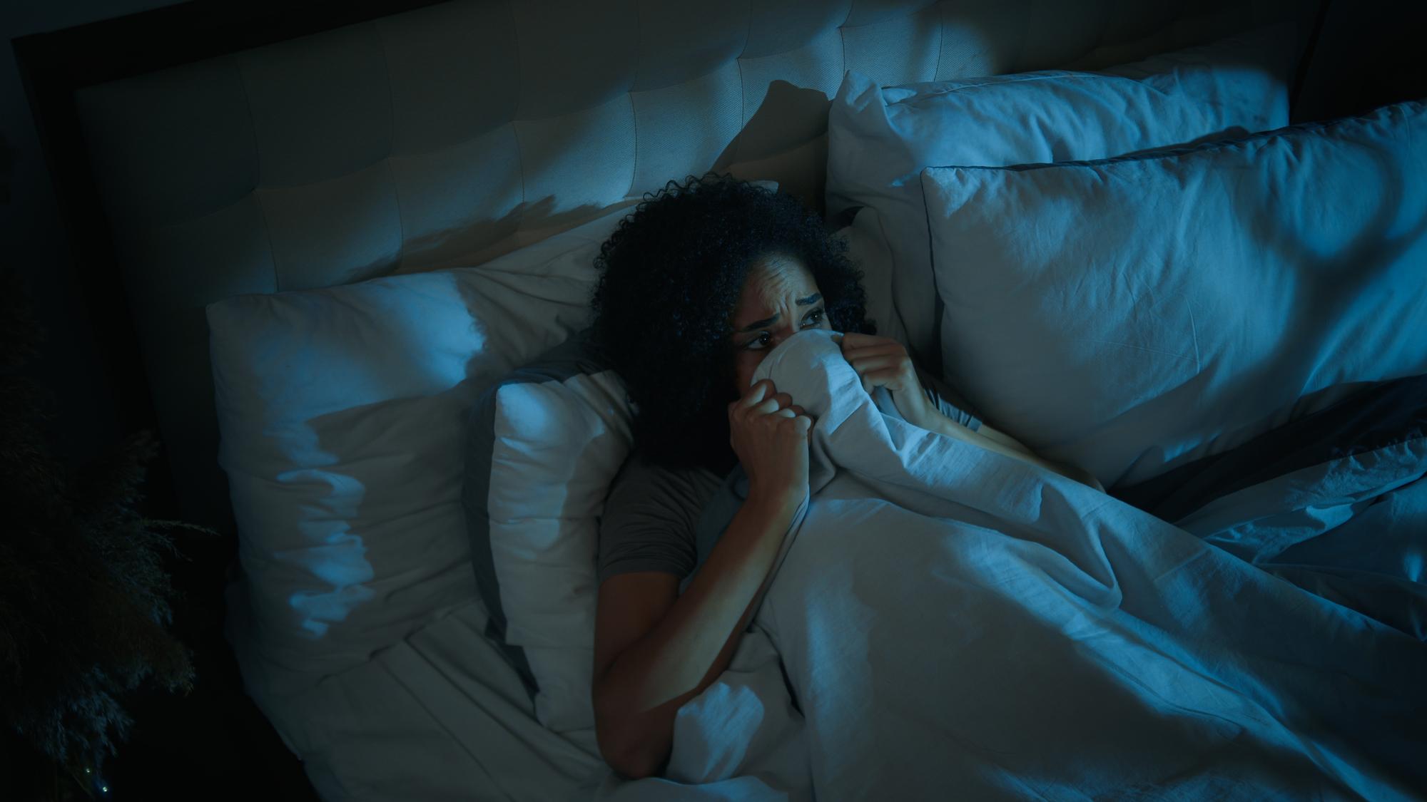 effrayée effrayée femme afro-américaine se cachant sous une couverture lit cauchemar trouble du sommeil mauvais rêve perturbé effrayé adolescente dans la chambre tard dans la nuit maison sombre peur nocturne peur effrayant monstre phobie