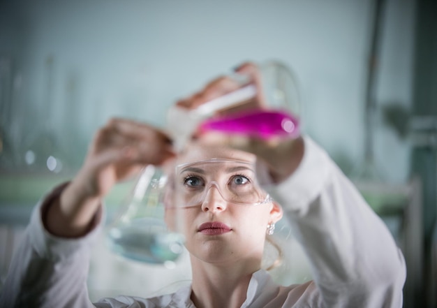 Laboratoire de chimie jeune femme blonde sur le point de verser un liquide rose dans la femme bleue au point