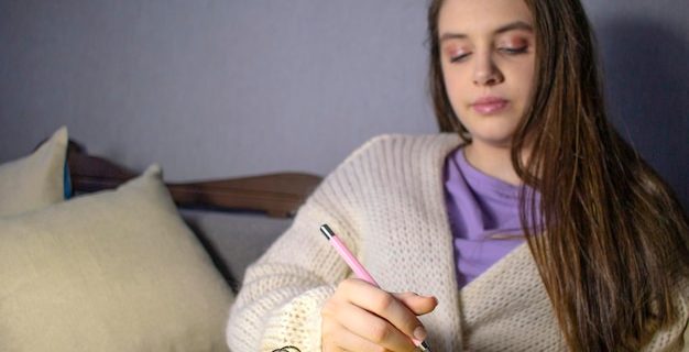 Adolescente faisant ses devoirs sur le canapé