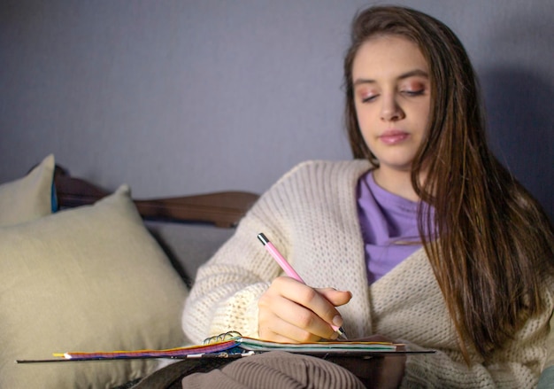 Adolescente faisant ses devoirs sur le canapé
