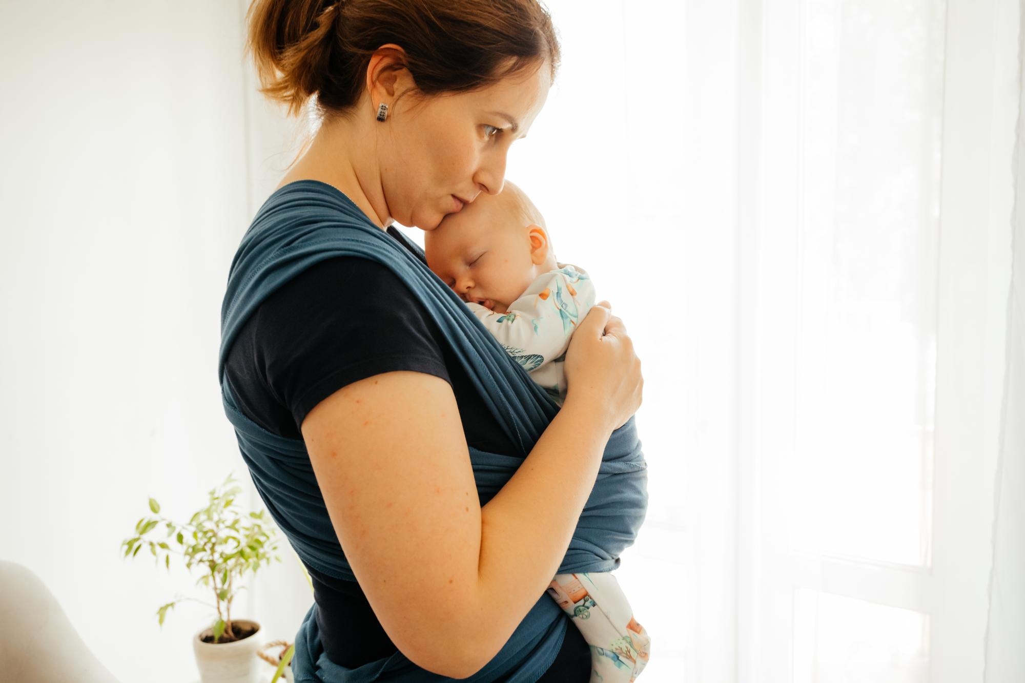 Concept parental d'attachement Jeune mère avec bébé en écharpe