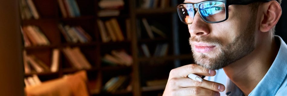 Homme d'affaires sérieux portant des lunettes d'ordinateur regardant l'écran de l'ordinateur avec la réflexion de l' ordinateur en utilisant Internet en regardant une formation de webinar en travaillant en ligne par vidéoconférence en vue du visage en gros plan