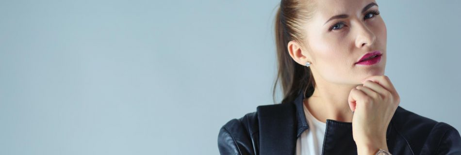 Portrait de la belle jeune femme brune en veste noire élégante sur gris