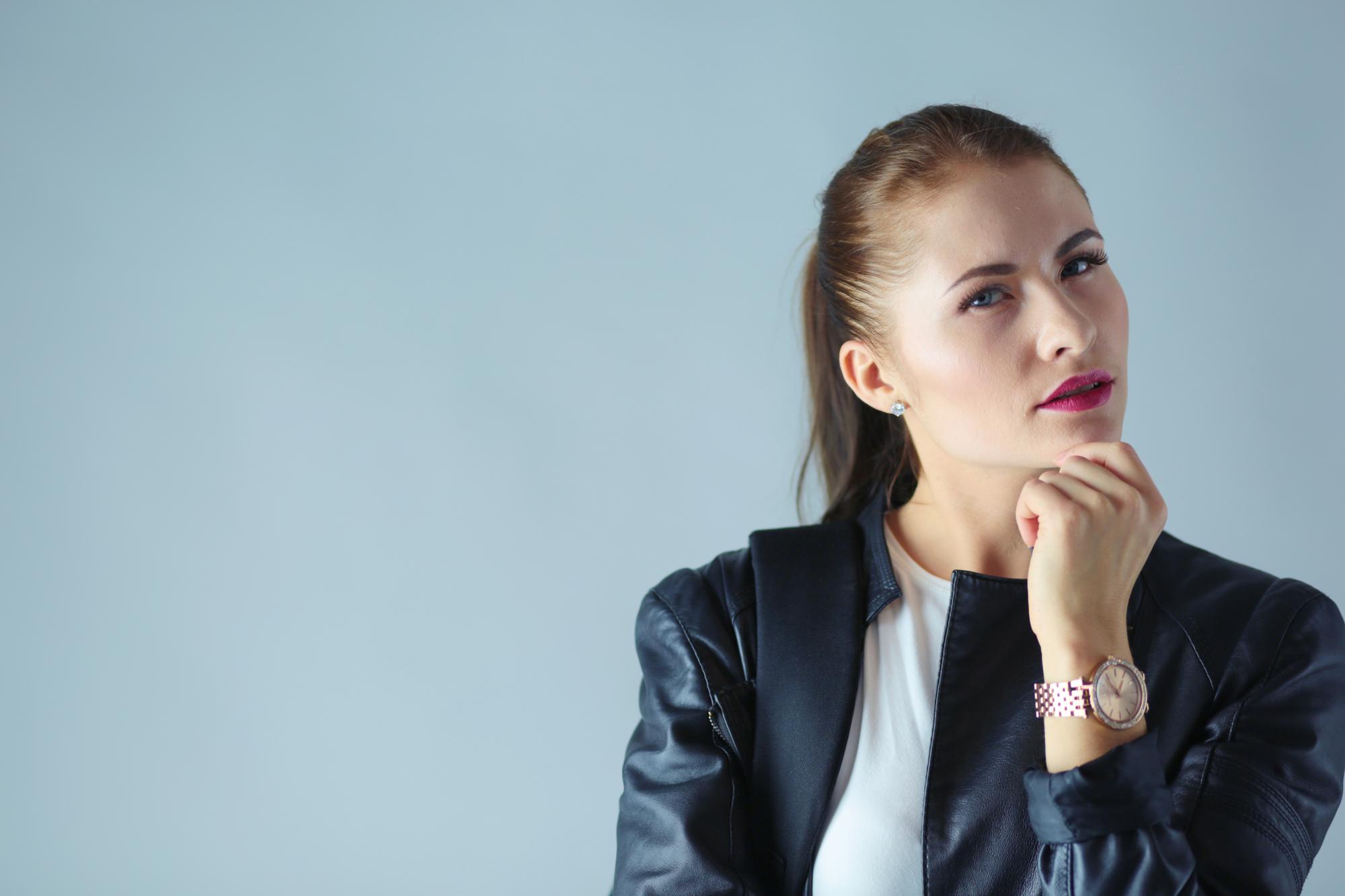 Portrait de la belle jeune femme brune en veste noire élégante sur gris